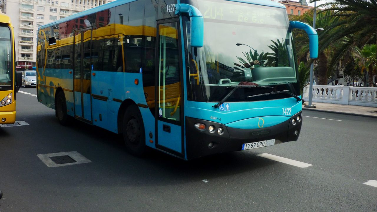 Una guagua turchese di Global e una guagua gialla di Guaguas Municipales affiancate in una via di Las Palmas de Gran Canaria